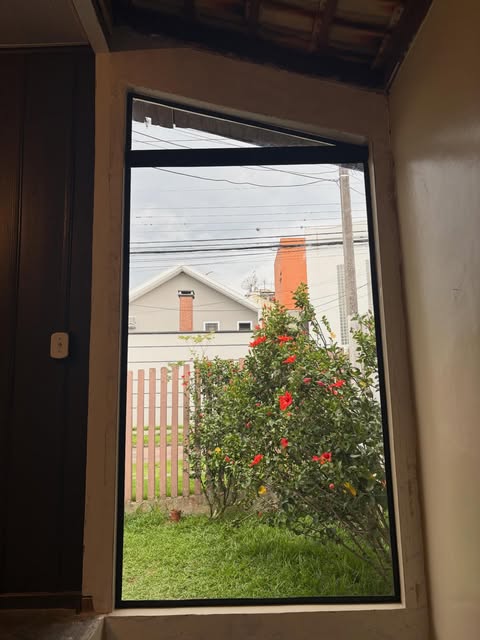 Janela de vidro temperado com moldura preta e jardim ao fundo